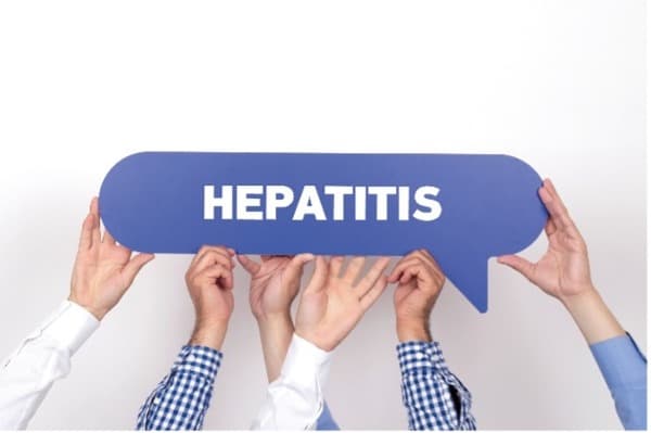 Photo of multiple hands holding up hepatitis text bubble.