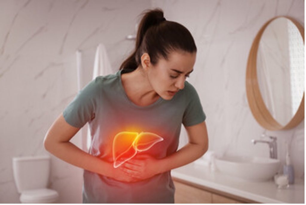 Woman holding stomach as if experiencing liver pain.